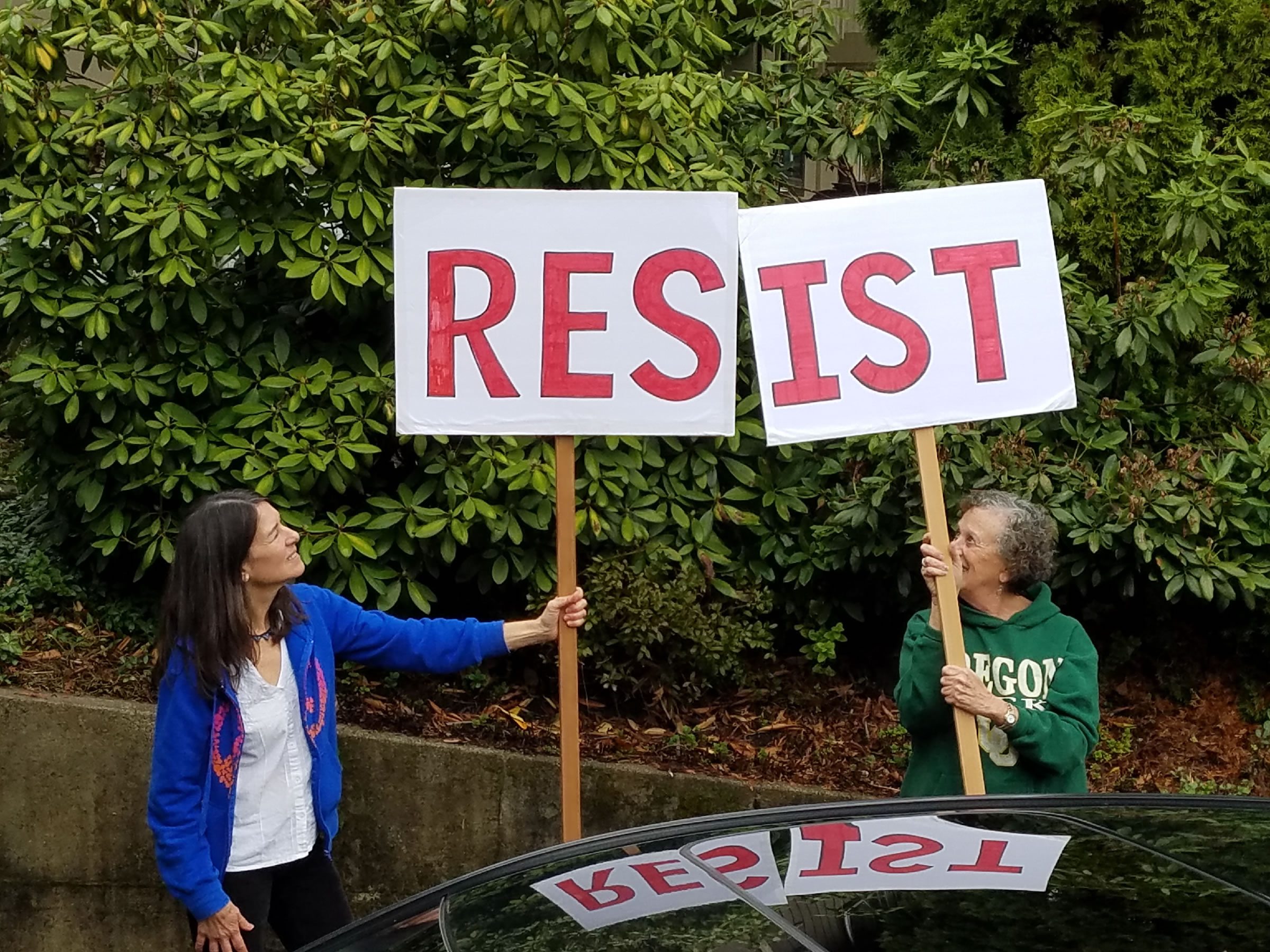 Photo of two women holding a large sign reading "Resist"